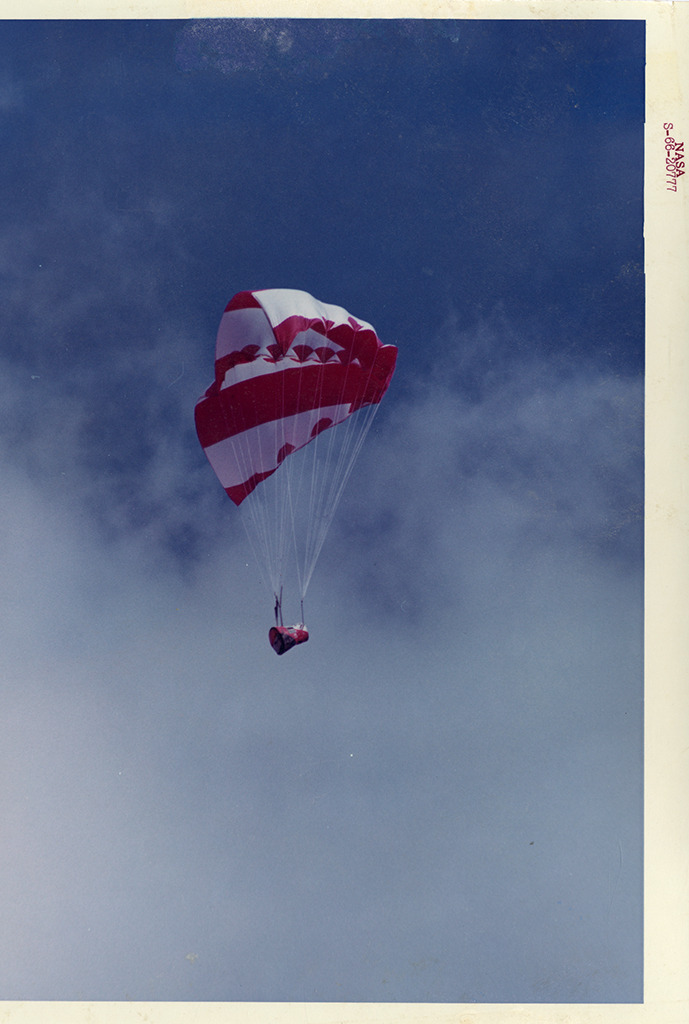 Photograph of the rogallo wing parachute holding up a space capsule