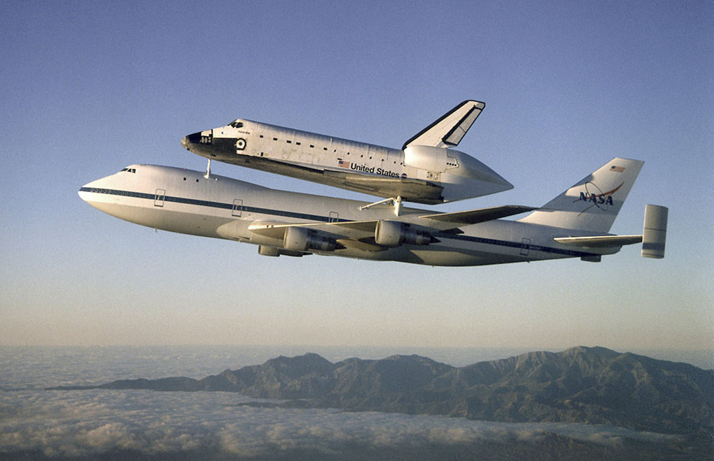 Atlantic space shuttle being transported on top of a NASA plane through the sky