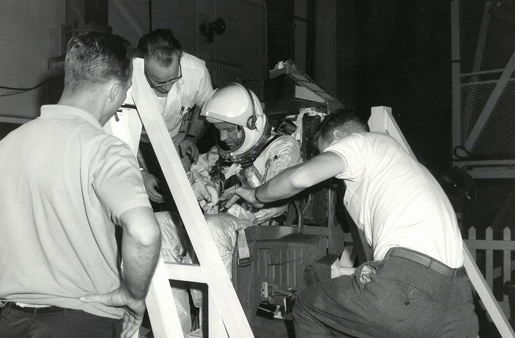 three men adjusting weight and balance of astronaut