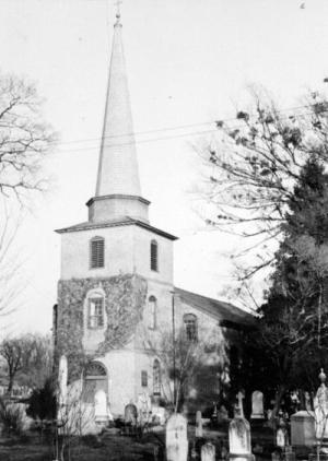 An ivy-covered church steeple with a cemetery in the foreground