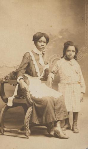 African American young woman in a maid's uniform with a girl, circa 1904-1918.