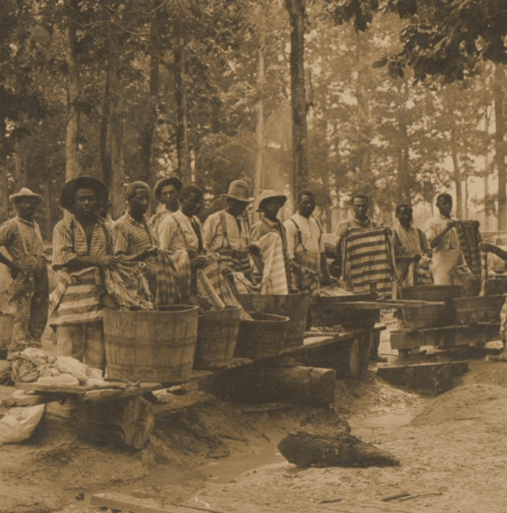A group of incarcerated laborers at a work camp in Mississippi wash their clothes in communal basins.